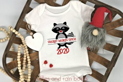 close up of baby onesie Valentines raccoon svg for stealin hearts on a farmhouse background