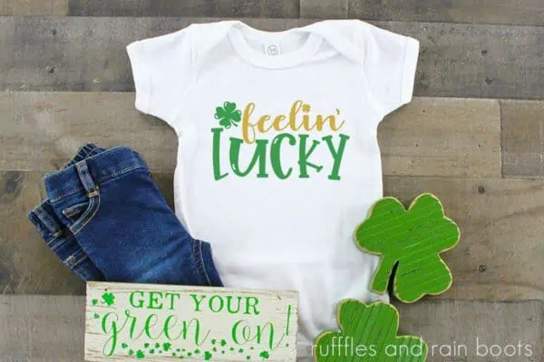 horizontal image of feelin lucky svg in gold and green for cricut on white t shirt with shamrock background