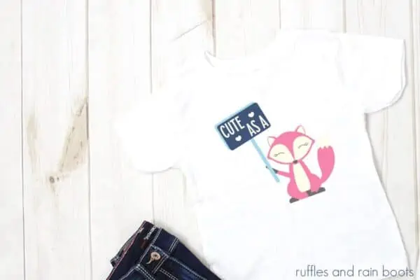 horizontal image of child white t shirt with pink and blue valentine fox svg on it holding a sign that says cute as a fox