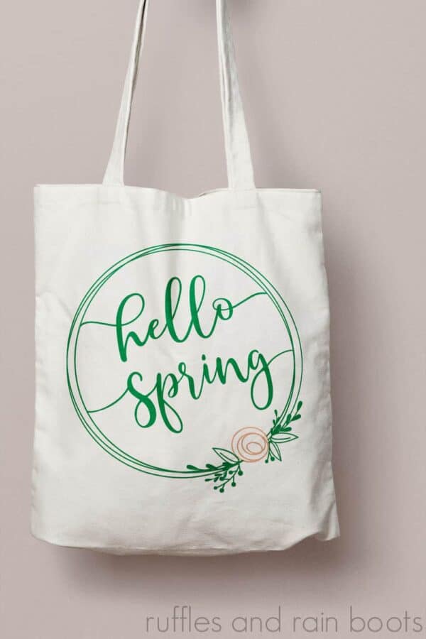 hello spring svg with wreath and flower on canvas tote bag and peach wall