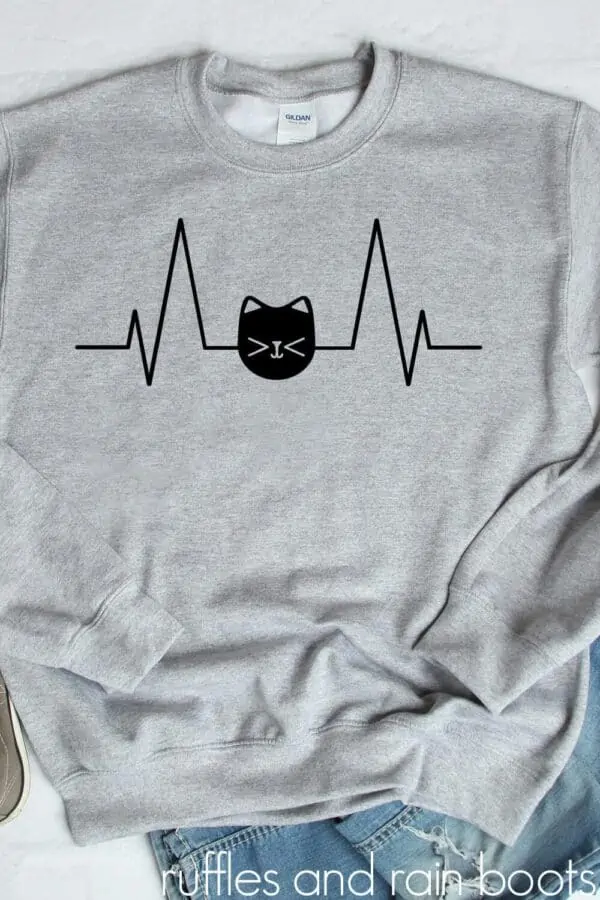 black cat heartbeat svg in vinyl on gray sweatshirt on white background with jeans