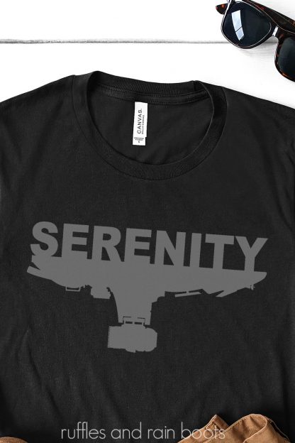 Serenity SVG placed in gray vinyl on black t shirt on white background