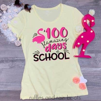 teacher shirt laying on a table featuring a 100 days of school flamingo svg cut file for cricut silhouette vinyl