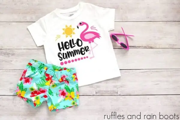 flamingo hello summer svg for cricut on a tshirt laying on a table with floral shorts