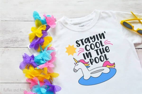 t-shirt laying on a table featuring the Stayin' Cool In the Pool Unicorn cut file set for summer crafts