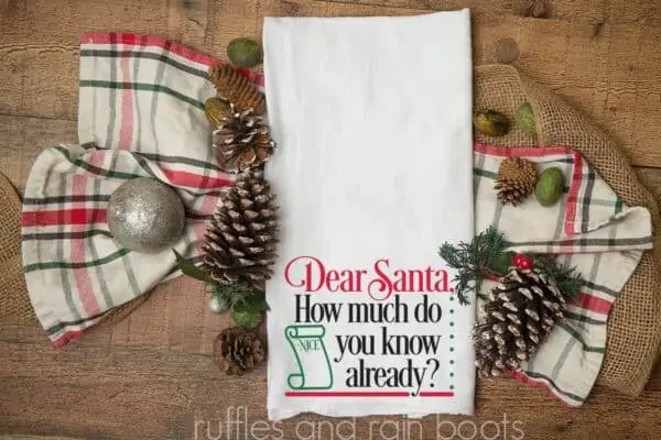 white flour sack towel on wood background with Dear Santa design in vinyl made with cricut