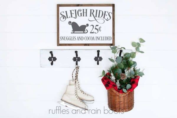 white wood wall with wood sign and gray sleigh rides illustration in svg form with ice skates and floral basket accents