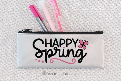 horizontal image of white skinny pen pouch with black and pink lettering in vinyl reading happy spring