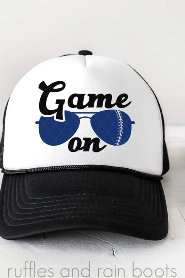 vertical image of white and black trucker hat with game on baseball svg with sunglasses on white background