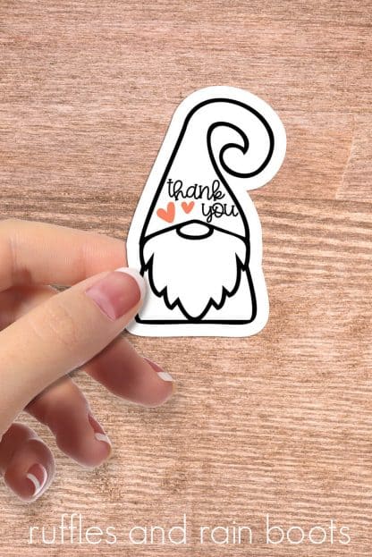 woman holding line art gnome with thank you sticker on wood background
