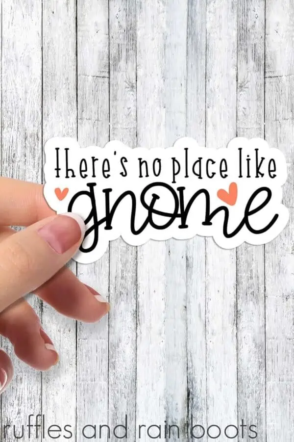 woman holding theres no place like gnome sticker on weathered white wood