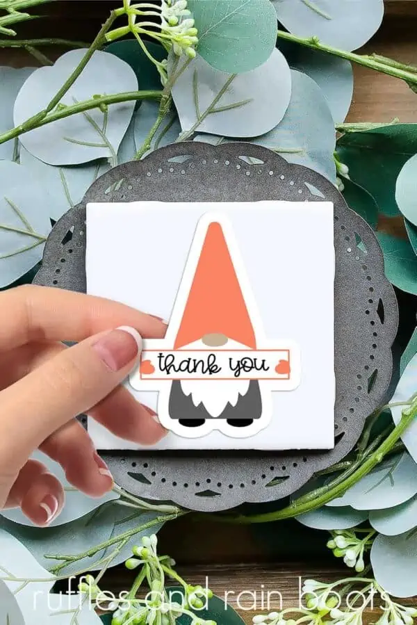 woman holding a gnome sticker with thank you sign on eucalyptus leaves