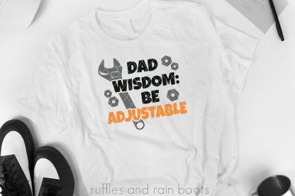 dad wisdom svg for father's day in orange black green and gray with wrench in vinyl on white t shirt
