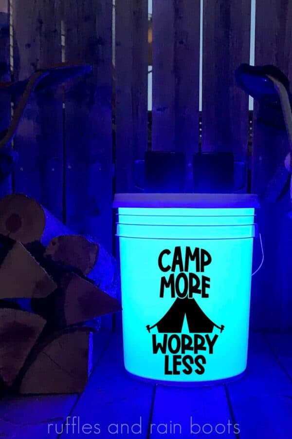 vertical image of camp more worry less in black vinyl on white camp bucket on wood porch