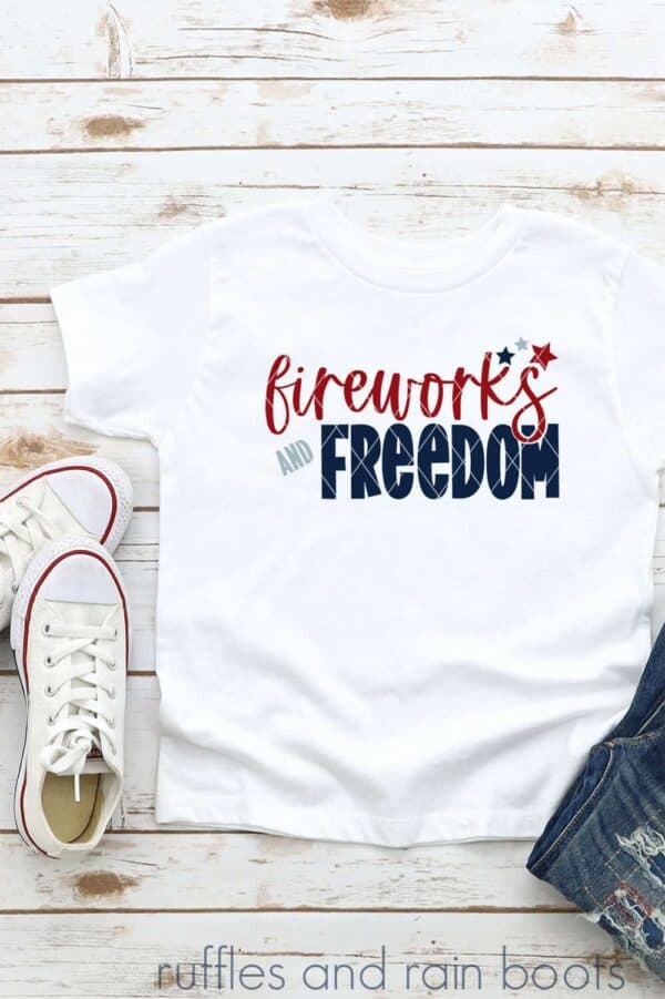 close up of white t shirt on white wood background with fireworks and freedom in red and blue