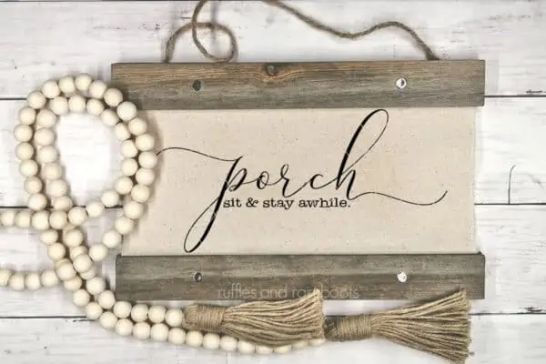 horizontal image of canvas wood hanging with porch sit and stay awhile svg with farmhouse beads on wood background