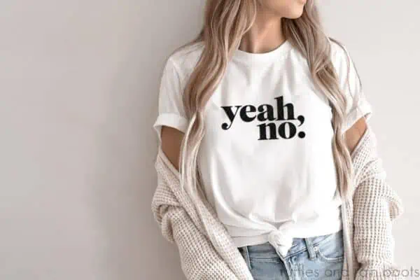 horizontal image of beige wall with woman in sweater and white t shirt with yeah no svg in bold design in black vinyl made on cricut