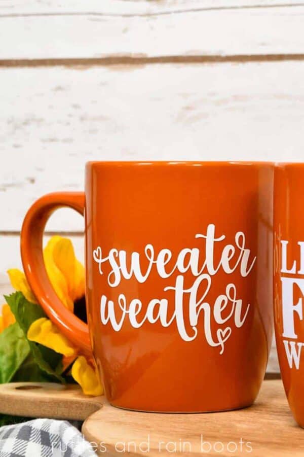 vertical close up of sweater weather mug made with free fall svg and placed in white vinyl made with Cricut Joy