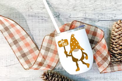 hello fall gnome cut file on white tumbler with straw on fall background with wood pinecones and buffalo check ribbon