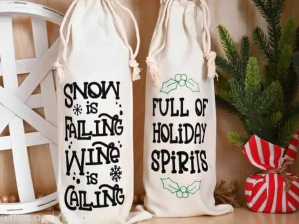 horizontal image of two Christmas wine bottle bags made with black and green flock heat transfer vinyl on Christmas background which reads snow is falling wine is calling and full of holiday spirits