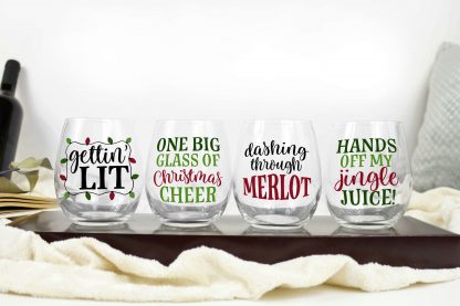 horizontal image of 4 stemless wine glasses on a cheese board with Christmas wine SVG designs in red green and black