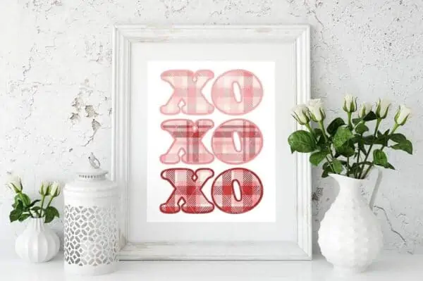 printed plaid XO Valentine sublimation placed in white wood frame with white vases and white concrete background