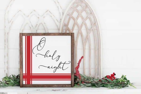horizontal image showing a holiday mantle with a wood Christmas sign which reads o holy night in a farmhouse style with a red flour sack grain sack design