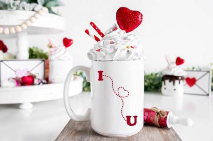 A dotted I heart you svg in red permanent vinyl cut with Cricut maker on white coffee mug in front of a Valentines Day background.