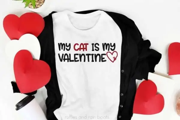 horizontal image of a white t shirt with black cardigan and paper hearts with my cat is my valentine svg in red and black with heart and paw