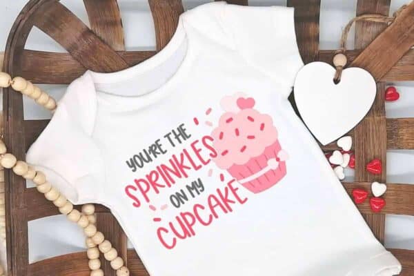 horizontal image of you're the sprinkles on my cupcake svg placed on a white body suit for valentines day or birthday from ruffles and rain boots