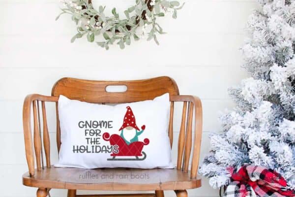 Horizontal image of a gnome in a sleigh on a holiday pillow which reads gnome for the holidays.
