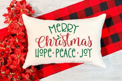 Horizontal image of a natural linen pillow on Buffalo check scarf background with Merry Christmas Hope Peace Joy in green and red HTV vinyl.