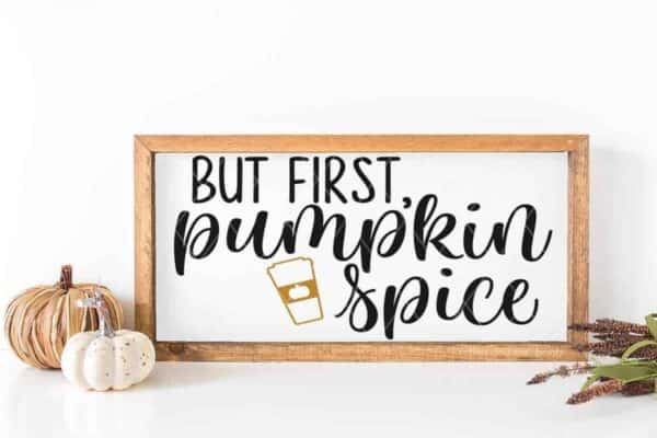 But first pumpkin spice svg in black and mustard vinyl made with Cricut on a wood frame sign in front of white background.