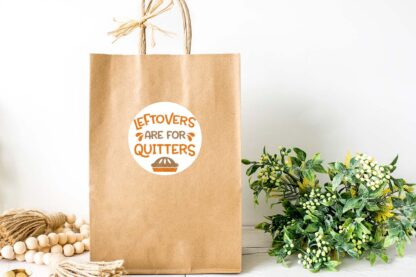 Horizontal image of a brown paper bag with leftovers are for quitters on a white sticker.