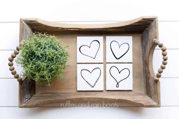 Horizontal image of four white coasters on farmhouse tray featuring free doodle heart SVG designs from Ruffles and Rain Boots.
