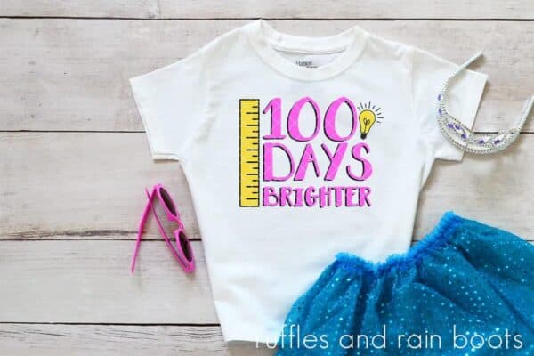 Blue sparkly tutu and crown with white t shirt which reads 100 days brighter made with ruler and lightbulb svg.