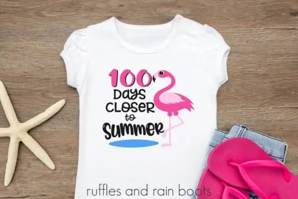 Dark wood background with pink flip flops and starfish with white t shirt which reads 100 days closer to summer.