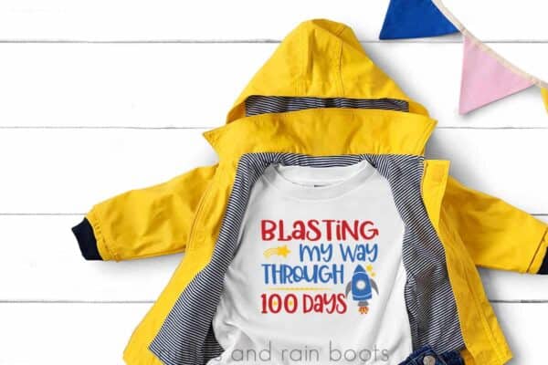 Yellow rain jacket with white t shirt which reads blasting my way through 100 days of school with rocket.