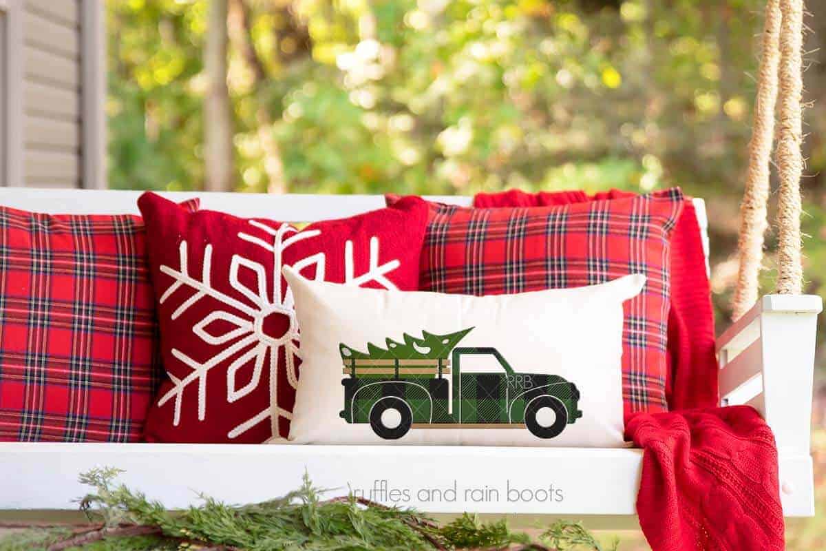 Horizontal image of holiday decorated porch swing with lumbar pillow with green Buffalo plaid Christmas truck.