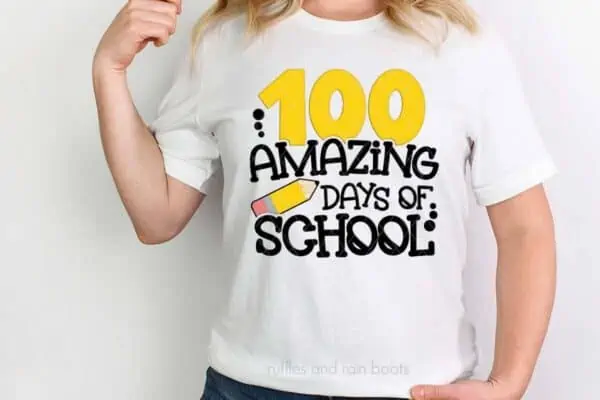 Horizontal image of woman wearing a white t-shirt which reads 100 amazing days of school with a pencil.