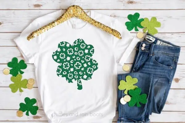 Horizontal image of white t-shirt with leopard shamrock SVG in green heat transfer vinyl made with Cricut on wood background.