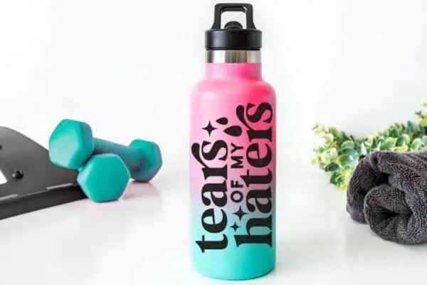 Horizontal image of pink and blue water bottle with black vinyl which reads tears of my haters.