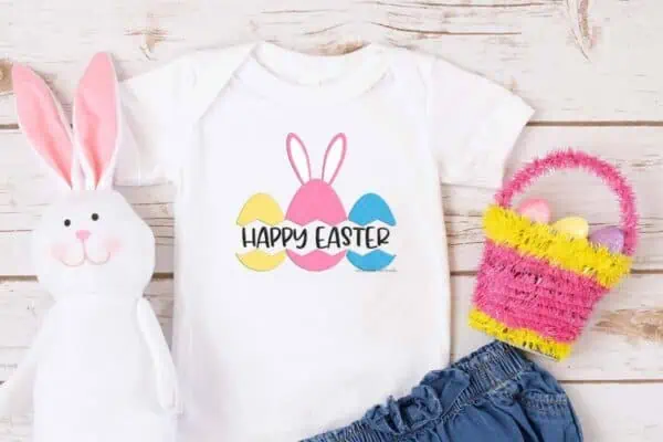 Horizontal image of white shirt and jean shorts with Happy Easter SVG split monogram in yellow pink and blue eggs.