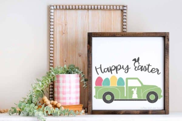 Horizontal image of candle, wood plank, and Easter sign which reads happy Easter with a market truck filled with eggs.