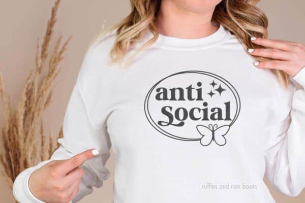 Horizontal image of woman in white long sleeve t-shirt made with a framed Antisocial Butterfly SVG free from Ruffles and Rain Boots.
