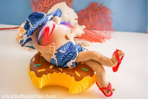 Horizontal image of beach gnome (summer gnome) in shorts, hat, and flip flops on a floatie.