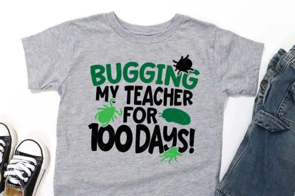 Horizontal image of gray shirt on white background which reads bugging my teacher for 100 days.