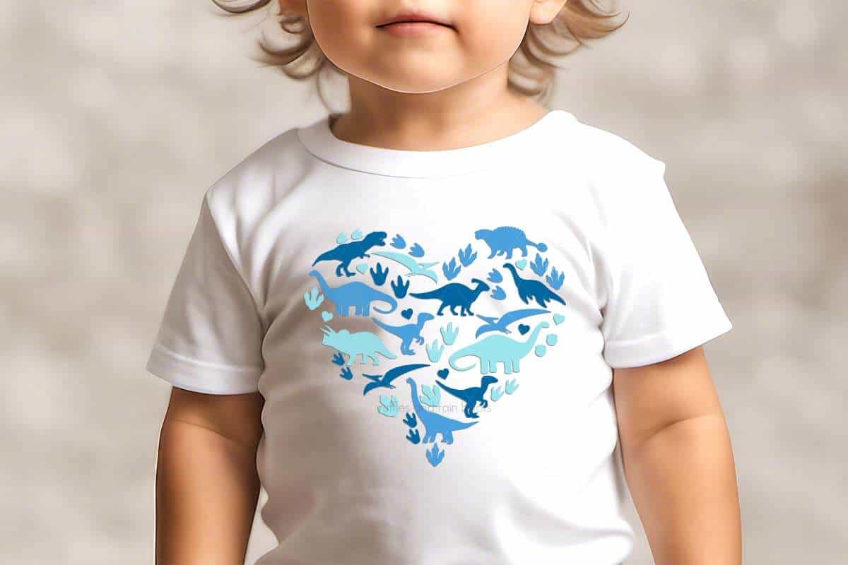 Heart made of dinosaur shapes and dinosaur footprints with hearts on a white t shirt on a little boy.