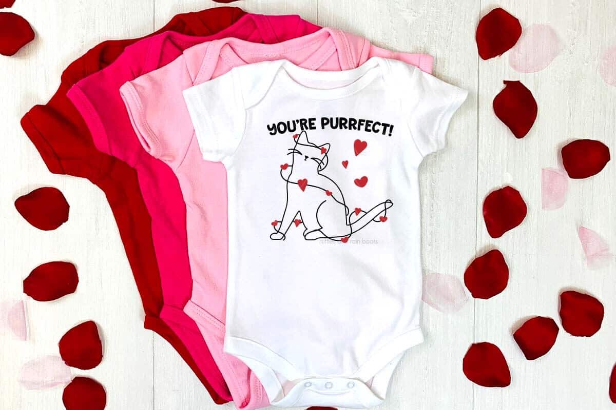 Horizontal image of a set of baby body suits with a cat outline SVG wrapped up in hearts.