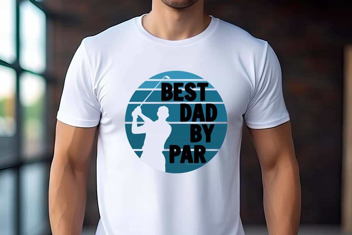 Horizontal image of a man in a warehouse wearing a white t-shirt which reads best dad by par with a golfer silhouette and a vintage background.